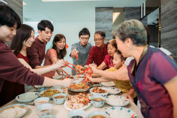 asiatisch-chinesische lächelnde familie feiert chinesischen silvesterabend mit rohem fischsalat "yusheng" während des wiedersehensessens - asian cuisine lunch dinner food stock-fotos und bilder