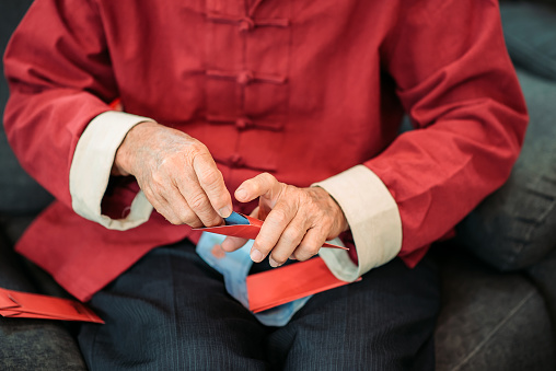 close up of grandfather sitting on sofa packing red envelope 