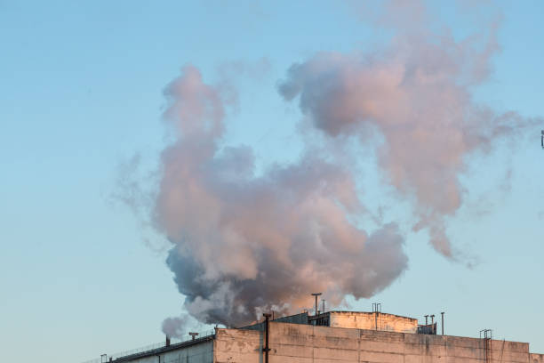 istock Brick chimney with white smoke over an industrial building 1358098977