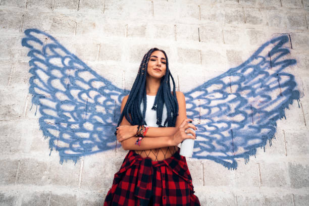 Rebel Caucasian woman, standing in front of the angel wings graffiti stock photo