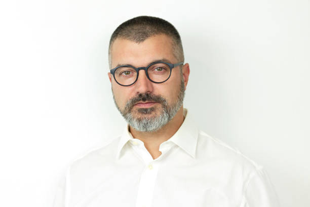 istock Handsome bearded man wearing eyeglasses and white shirt looking at camera 1358100189