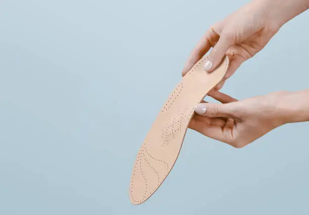 Orthopedic insole isolated on a blue background. Medical insoles. Treatment and prevention of flat feet and foot diseases. Foot care, feet comfort. Wear comfortable shoes. Flat Feet Correction.