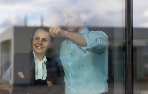 istock Contemplative business couple making discussion next to office window 1358101427