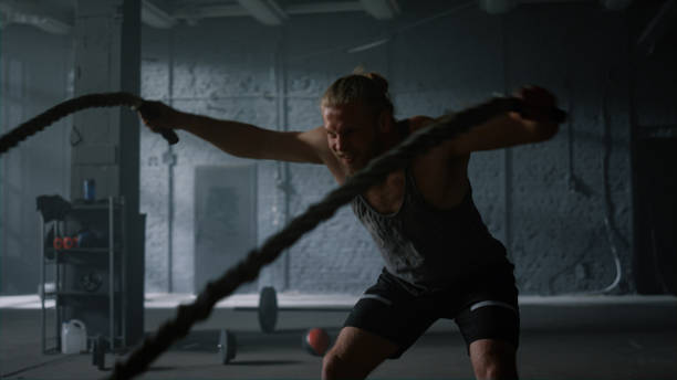 istock Bodybuilder working with battle ropes. Athletic man practicing fitness exercise 1358101466
