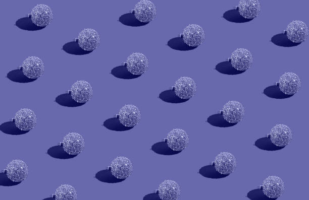 istock Simple pattern made of golden baubles on lavender background. Creative winter composition. Christmas party and festive concept. Minimal style. Color of the year 2022 inspired 1358105088