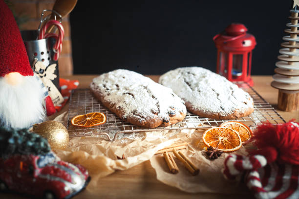 istock Christmas background. Christstollen covered with powdered sugar. Table full of kitchen utensils and Christmas decoration. Homemade Christmas stollen bread. 1358106138