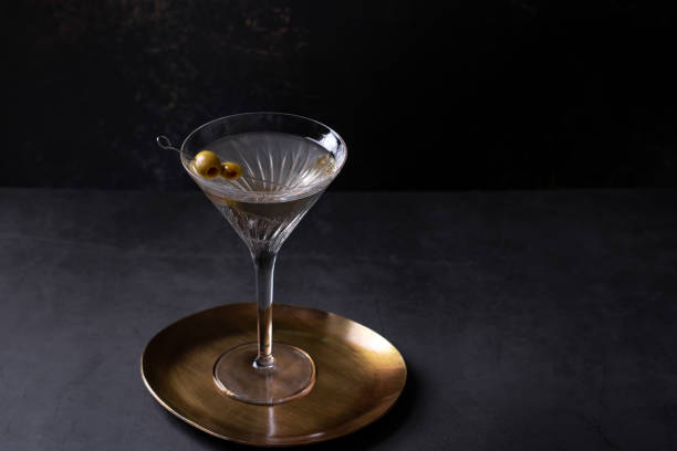 istock Dirty martini cocktail in martini glass with olives garnish on dark table 1358106421