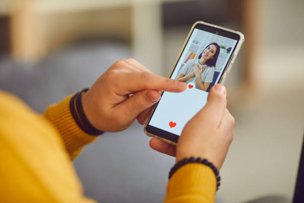 man uses a smartphone to flip through women's profiles and presses a heart button with his finger. - internet dating imagens e fotografias de stock