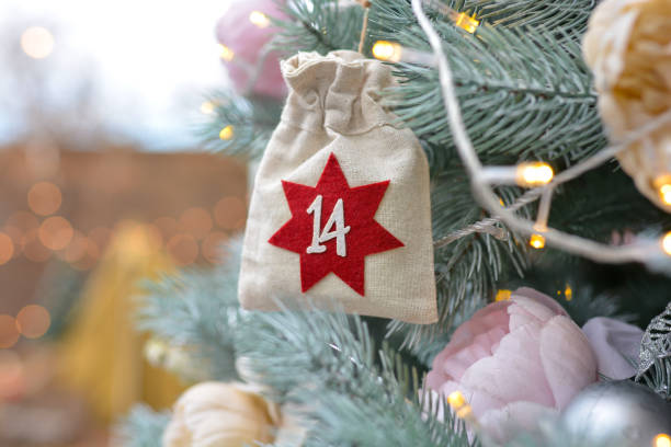 antecedentes navideños. calendario de adviento en forma de bolsas ecológicas colgadas en un árbol de navidad bellamente decorado. regalos y tareas navideñas - advent calendar christmas number number 14 fotografías e imágenes de stock