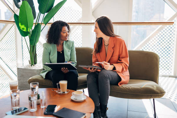 istock Two female colleagues are talking casually during a coffee break in a modern office. 1358110505