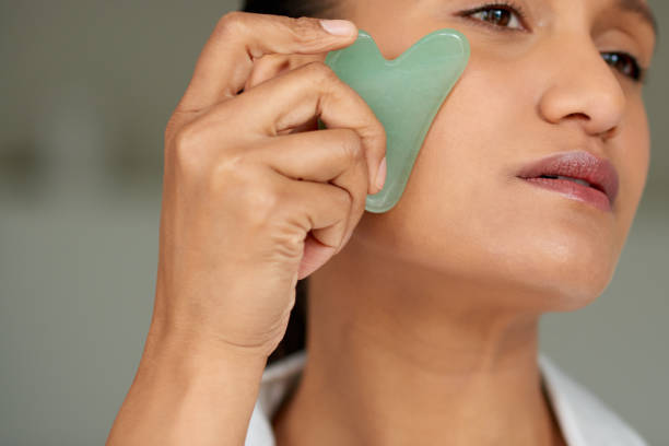 istock Closeup shot of a beautiful woman using a scraping tool on her face 1358110729