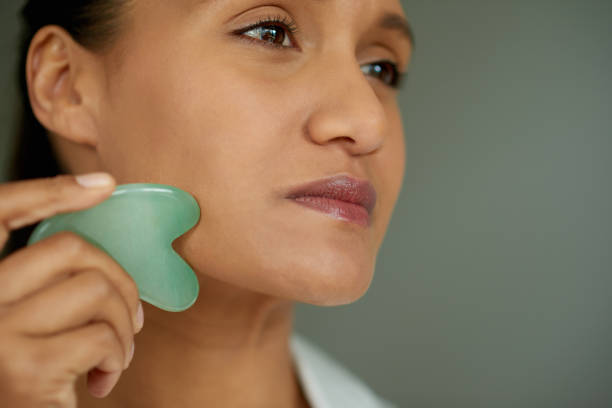 istock Closeup shot of a beautiful woman using a scraping tool on her face 1358110735