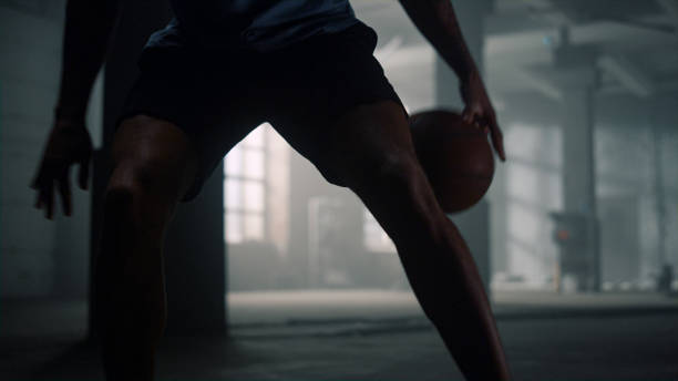 istock Basketball player playing game. Man bouncing basketball ball between legs 1358121487