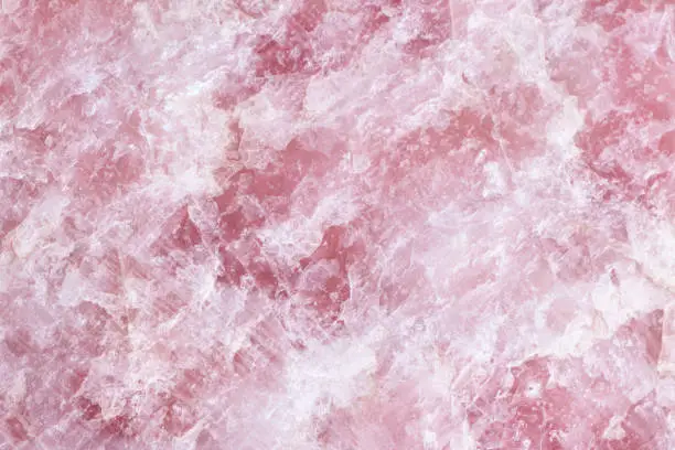 Photo of Raw Rose quartz stone textured surface background.