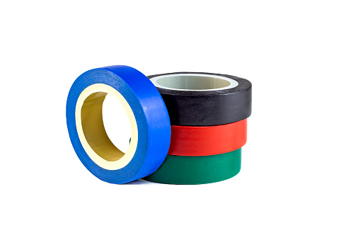 Red, green and blue adhesive insulating electrical tape reels stack isolated on white background.