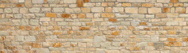 istock Light brown stone wall in panoramic close-up made of natural stones 1358126321