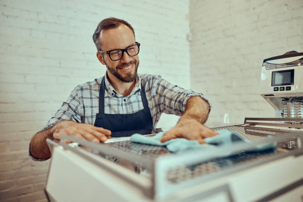 istock Joyful male bartender cleaning coffee machine in cafe 1358127644
