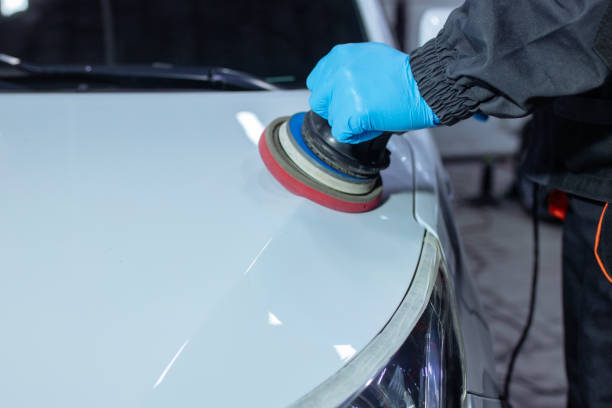 istock Serviceman polishing car body with machine in a workshop. 1358128294