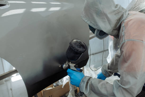 istock Professional car painter is painting in garage by airbrush. 1358128533