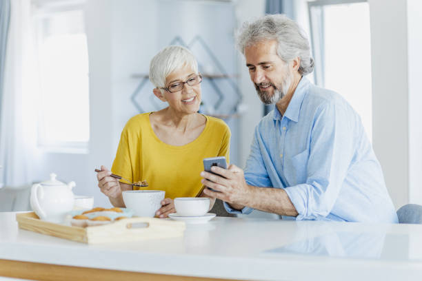 istock Senior couple taking breakfast at home and using mobile phone 1358131085