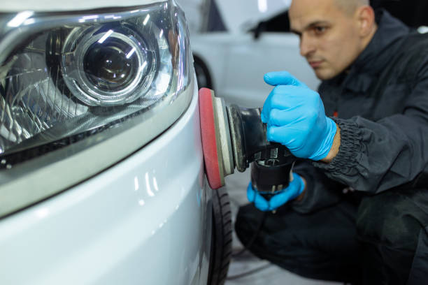 istock Serviceman polishing car body with machine in a workshop. 1358131258