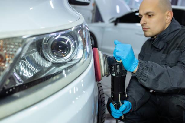 istock Serviceman polishing car body with machine in a workshop. 1358131361