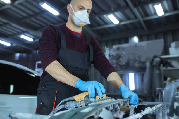 Sanding a car body part with electrical grinder machine before painting, vehicle body repair service. Sanding a car body part with electrical grinder machine before painting, vehicle body repair service grinding metal power work tool stock pictures, royalty-free photos & images