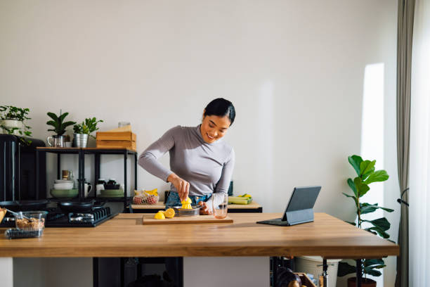 happy woman squeezing lemon in kitchen - 僅成年人 個照片及圖片檔