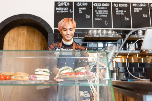 barista aranżujący świeżo przygotowane jedzenie w kawiarnianej ladzie ekspozycyjnej - praca w niepełnym wymiarze zdjęcia i obrazy z banku zdjęć