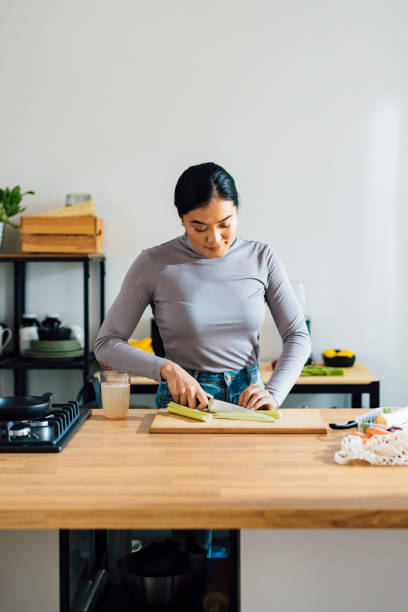 istock Beautiful Woman Cutting Leek on a Cutting Board 1358132459