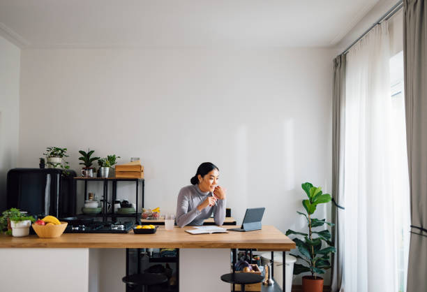 Happy Business Woman Working from Home Beautiful Asian businesswoman using digital tablet at kitchen desk. home office stock pictures, royalty-free photos & images