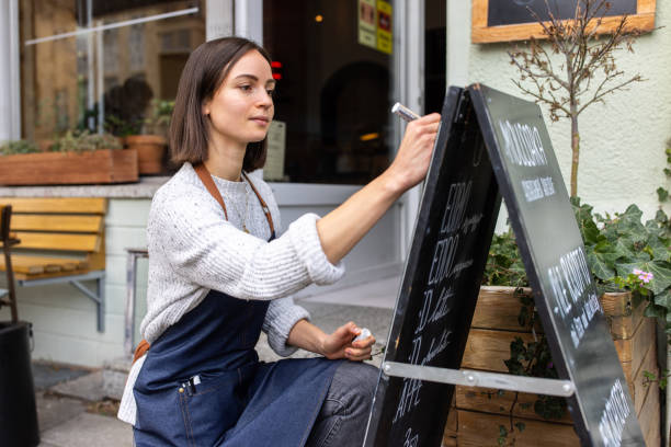 Woman cafe owner writing special menu on the chalkboard