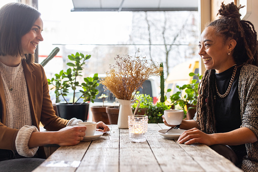Young woman meeting a with a female colleague at cafe. Two businesswomen talking while having a coffee at restaurant.
