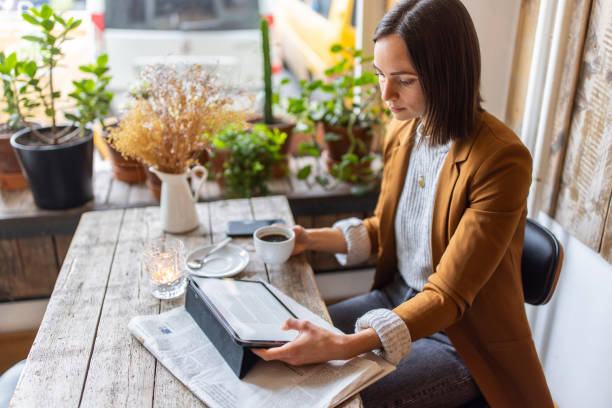 mujer de negocios sentada en una cafetería usando una tableta digital - medios de comunicación fotografías e imágenes de stock