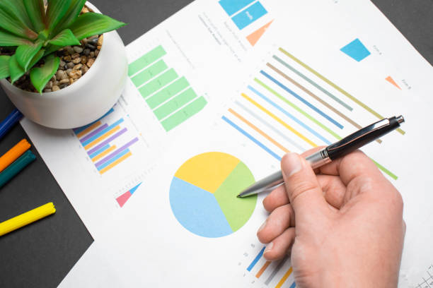 istock hand with a pen writing on the business paper. Report chart 1358136485