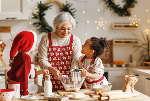 glückliche multirassische kinder helfen großmutter, in den winterferien weihnachtsplätzchen in der küche zu kochen - grandmother cooking baking family stock-fotos und bilder