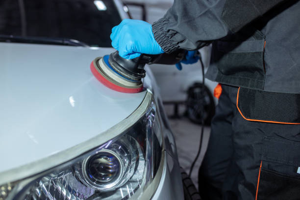 istock Serviceman polishing car body with machine in a workshop. 1358140043
