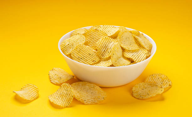 istock Ridged potato chips in bowl on yellow background 1358140540