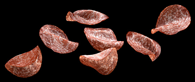 Falling salami sausage slices isolated on black background