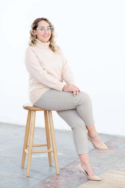 happy obese woman with glasses in warm sweater sits on stool - high stool imagens e fotografias de stock