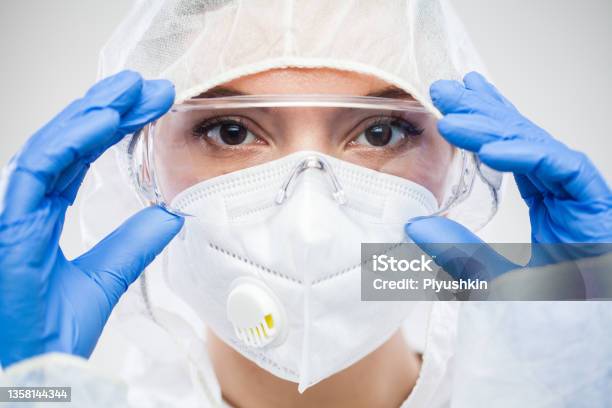 Female Nhs Doctornurse Or Lab Tech Virology Scientist In Ppeputting On Protective Eyewear Goggles Stock Photo - Download Image Now