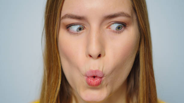 istock Closeup cheerful woman making funny faces on grey background in studio. 1358145460