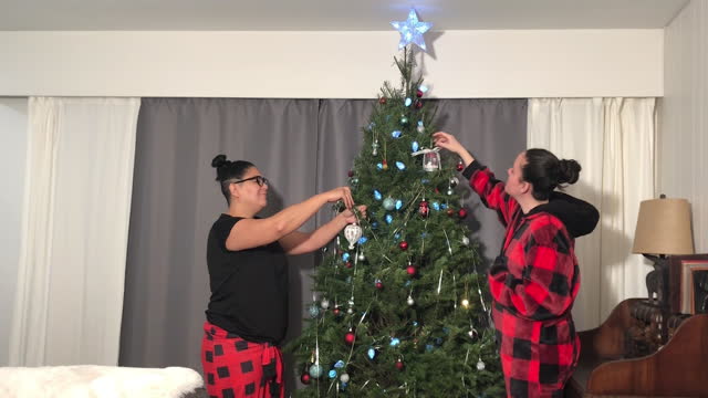 interracial lesbian couple decorating the Christmas tree