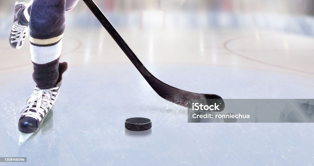 Close up of ice hockey player with stick on ice rink controlling puck Low angle view of ice hockey player with stick on ice rink controlling puck and copy space. Hockey Stock Photo