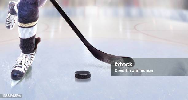 Close Up Of Ice Hockey Player With Stick On Ice Rink Controlling Puck Stock Photo - Download Image Now