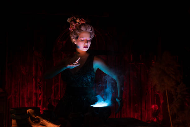 halloweenowa czarownica z kotłem. piękna młoda kobieta wyczarowująca, tworząca czary - aphrodisiac zdjęcia i obrazy z banku zdjęć