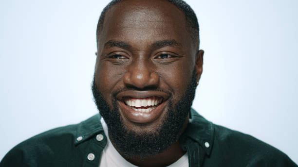 istock Portrait of smiling african guy laughing at camera on light background 1358154823