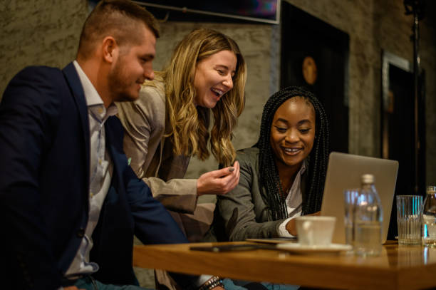 istock Cheerful work colleagues working on a laptop while having a meeting in a cafe 1358154904