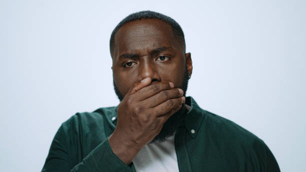 istock Portrait african man checking breath freshness in studio. Guy preparing for date 1358154993