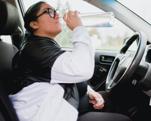 istock Woman Driving Car and Drinking Water Bottle 1358155046